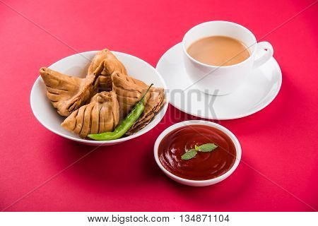 Samosa snack with tomato ketchup and hot tea, Fresh samosas with ketchup and hot chai ready for breakfast