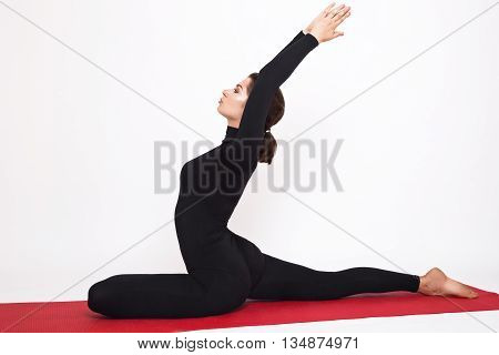 Beautiful athletic girl in a black suit doing yoga. Eka Pada Radzhakapotasana asana - pigeon pose royal. Isolated on white background.