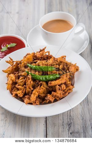 Crispy onion bhaji or kanda bhaji or fried onion pakore or pakode, delicious street food, favourite indian snack in monsoon served with hot tea