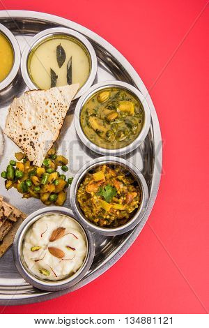 typical maharashtrian food served in a steal plate, marathi food includes kadhi and shrikhand, plain dal, spinach curry, aalu mutter, plain rice, papad, bhakri or bhakar or roti and variety of salad