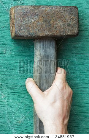 The white man wants to take a hammer lying on the table.