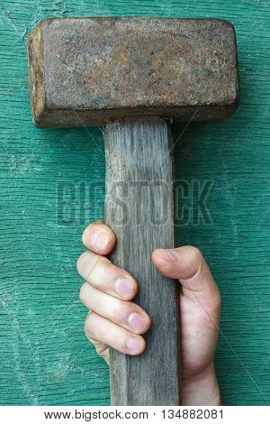 The white man wants to take a hammer lying on the table.