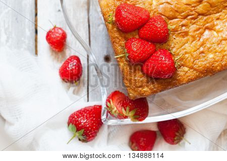 Piece of sponge cake with strawberry topping on the old white wooden table top view
