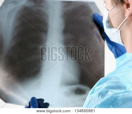 Doctor in blue uniform holding X-rays. clinic