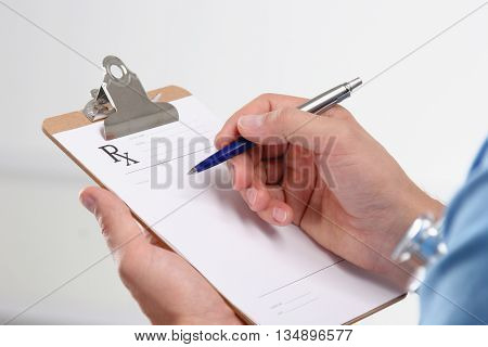 Male doctor writing prescription on clipboard. clinic