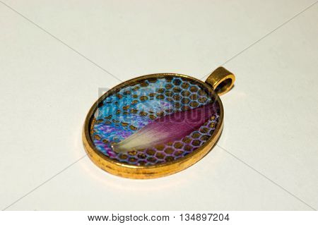 Brass color pendant with blue lace and gerbera petal inside the epoxy resin.