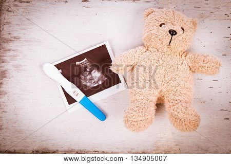 ultrasound with pregnancy test on wooden background