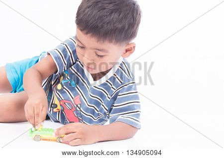little boy lying play car toy on white background