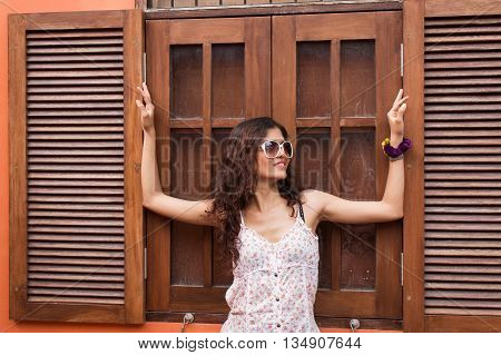 Portrait of beautiful woman standing at wooden window