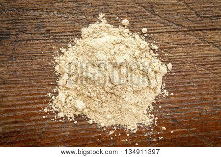 heap of red maca root powder against rustic weathered wood