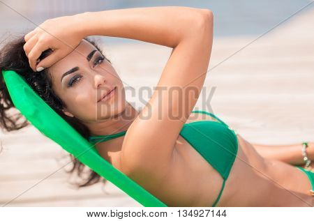 Young attractive woman in swimwear posing in caise-lounge on the beach.
