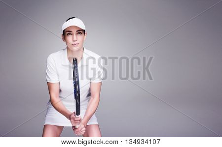 Female athlete playing tennis against grey background