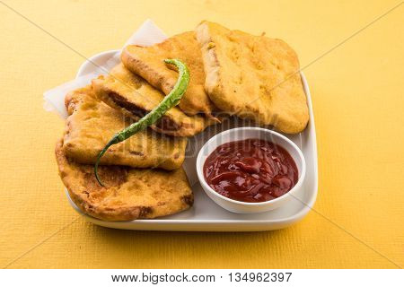 Bread Pakora or bread pakoda served along with tomato ketchup green chilly and onion slices, indian snack