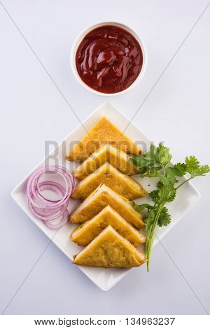Bread Pakora or bread pakoda served along with tomato ketchup green chilly and onion slices, indian snack