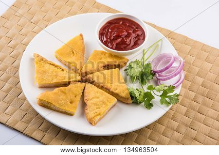 Bread Pakora or bread pakoda served along with tomato ketchup green chilly and onion slices, indian snack
