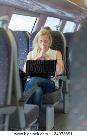 Businesswoman sitting and traveling by train working on laptop.