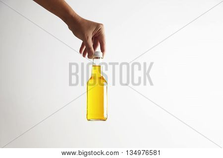 Hand puts down closed rustic glass bottle with tasty cold drink inside, isolated on white in center