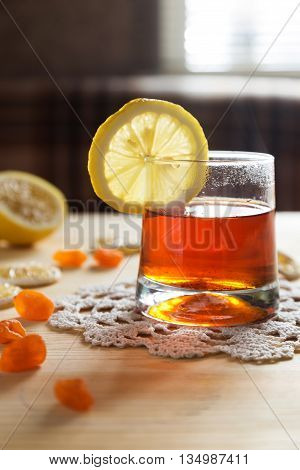 A photo of a glass of hot tea and a lemon slice