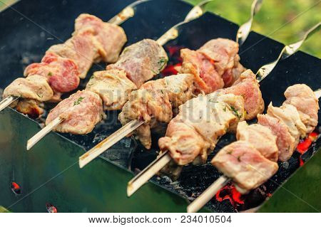 Pieces Of Pork Being Roasted On Skewers Over Charcoal In Braizer