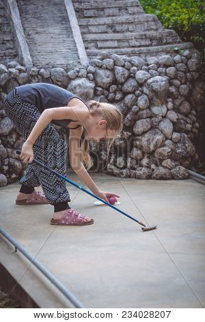 Happy Little Girl  Playing Mini Golf.