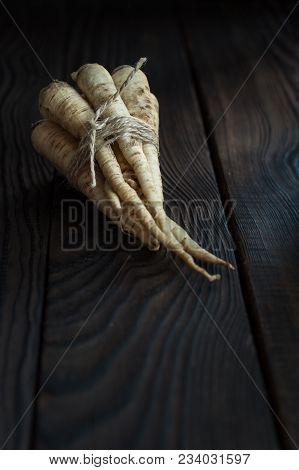 A Bunch Of Parsley Root On A Dark Wooden Table