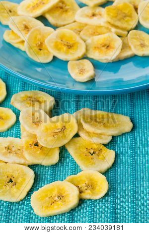 Heap Of Dried Banana Chips Snack On Blue Turquoise Plate And Mat On Table