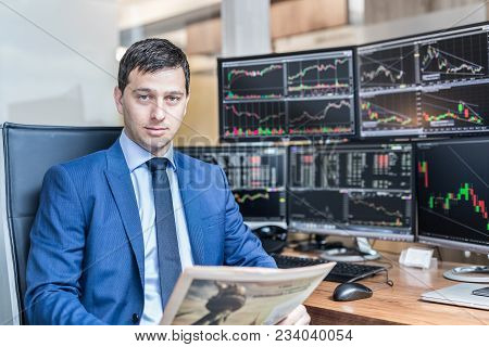Business Portrait Of Confident Stocks Broker Holding A Business Newspaper In Traiding Office With Mu