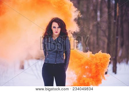 Girl Brunette Against The Background Of The Winter Forest Colored Orange Smoke Fire
