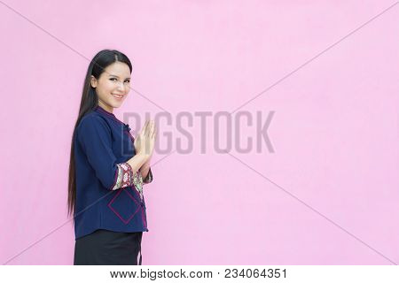 Portrait Of Asian Girl Young In Traditional Thai Dress Praying Isolated On Pink Background. Wai Sawa