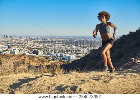 fit african american woman running at runyon canyon with los angeles in background