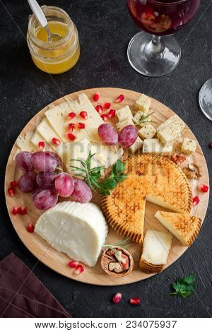 Cheese Platter With Assorted Cheeses, Grapes, Nuts Over Black Background, Copy Space. Italian Cheese