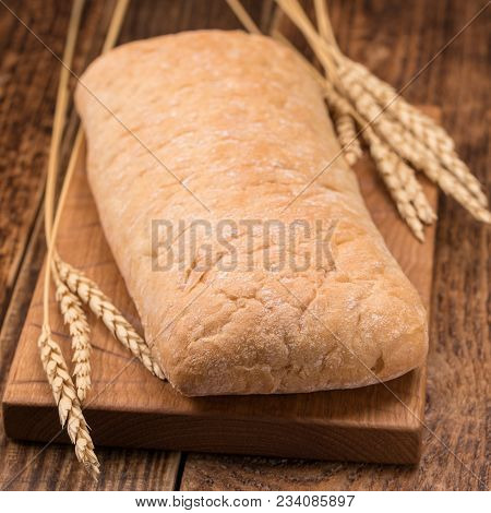 Fresh Tasty Homemade Bread On A Wooden Board. A Monotonous Still Life With Bread And Spikelets Of Ry