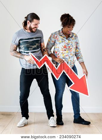 Unhappy interracial couple holding a downward arrow risk and fail concept