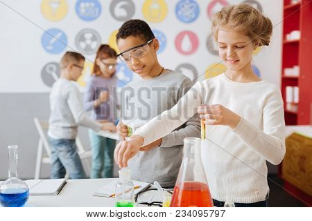 Interesting Chemistry. Charming Teenage Girl Holding A Test Tube With A Chemical And Taking Some Mil