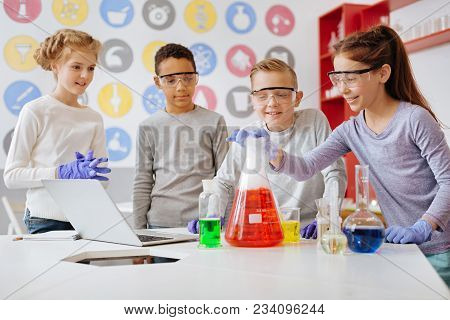 Interesting Experiment. A Group Of Cheerful Students Being Gathered Around The Table During Their Ch