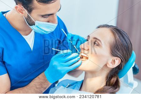 Young and beautiful woman looking with confidence at her reliable dentist during safe and painless dental treatment in a modern clinic