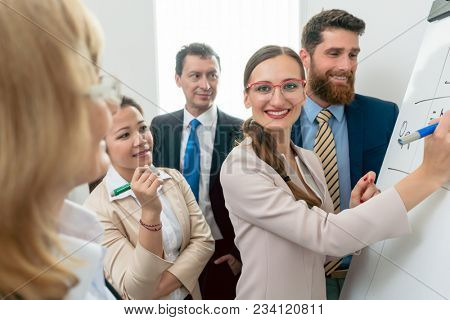 Portrait of a proficient business woman smiling, while analyzing the opportunities of a new project during an interactive meeting with the board of directors in the office