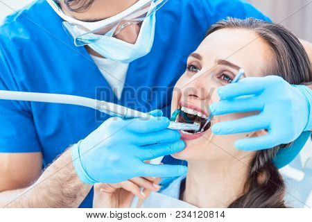 Side view close-up of a relaxed young woman during painless oral treatment in the modern dental office of an experienced and dedicated dentist