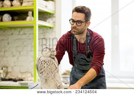 Portrait of Ceramist Dressed in an Apron Working on Clay Sculpture in the Bright Ceramic Workshop.