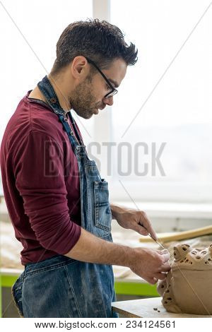 Ceramist Dressed in an Apron Sculpting Statue from Raw Clay in the Bright Ceramic Workshop.