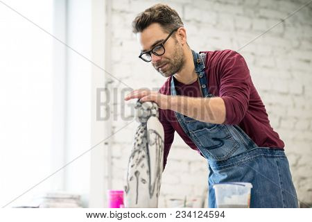 Portrait of Ceramist Dressed in an Apron Working on Clay Sculpture in the Bright Ceramic Workshop.