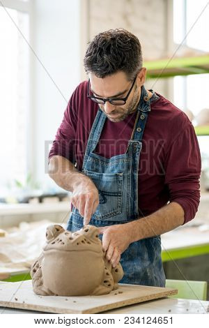 Ceramist Dressed in an Apron Sculpting Statue from Raw Clay in the Bright Ceramic Workshop.