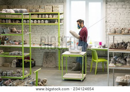 Portrait of Ceramist Dressed in an Apron Working on Clay Sculpture in the Bright Ceramic Workshop.