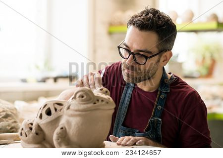 Ceramist Dressed in an Apron Sculpting Statue from Raw Clay in the Bright Ceramic Workshop.
