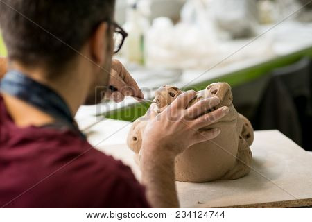 Ceramist Dressed in an Apron Sculpting Statue from Raw Clay in the Bright Ceramic Workshop.