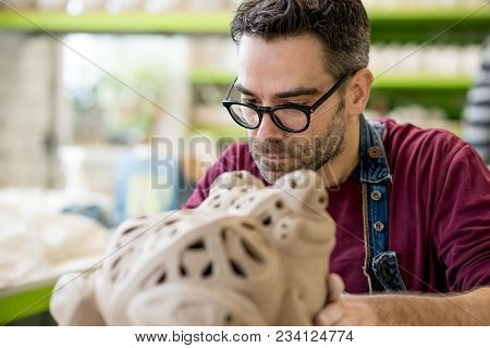 Ceramist Dressed in an Apron Sculpting Statue from Raw Clay in the Bright Ceramic Workshop.