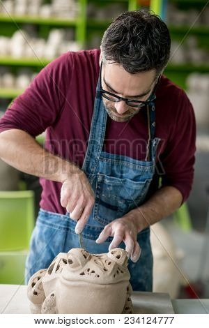 Ceramist Dressed in an Apron Sculpting Statue from Raw Clay in the Bright Ceramic Workshop.