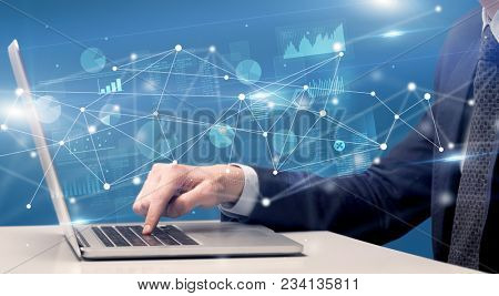 Businessman typing on laptop with linked reports charts grapghs around