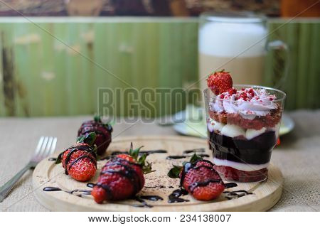 Dessert Trifle With Blueberry Cream , Strawberries And Gkass Of Coffee Latte Back On A Green Wooden 