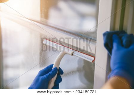 Young Man Is Using A Rag And Squeegee While Cleaning Windows.